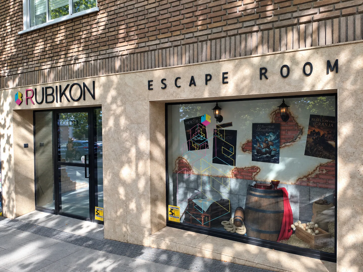 Rubikon's window display with posters for The Room 745, Magellan's Secret and Chicken Rebellion, beside a wooden barrel and fruit crates